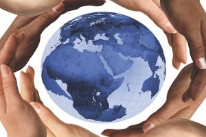 People hold a small globe in their hands, symbolizing global connection and international awareness.