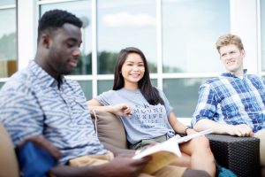 Students sit outside in a group with books open