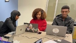 Students work together while sitting around computers