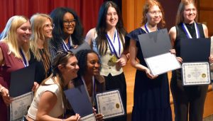 Students pose together and smile while holding certificates