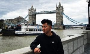 Student poses in front of a bridge