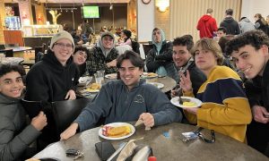 Students gather around a table and pose in the dining hall