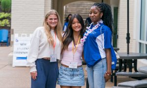 A group of students pose wearing lanyards and leis.