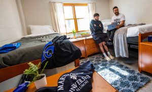 Students look at a computer while in their dormitory