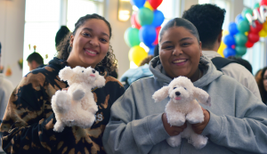 Students pose holding stuffed animal dogs for Bernie's birthday celebration. 