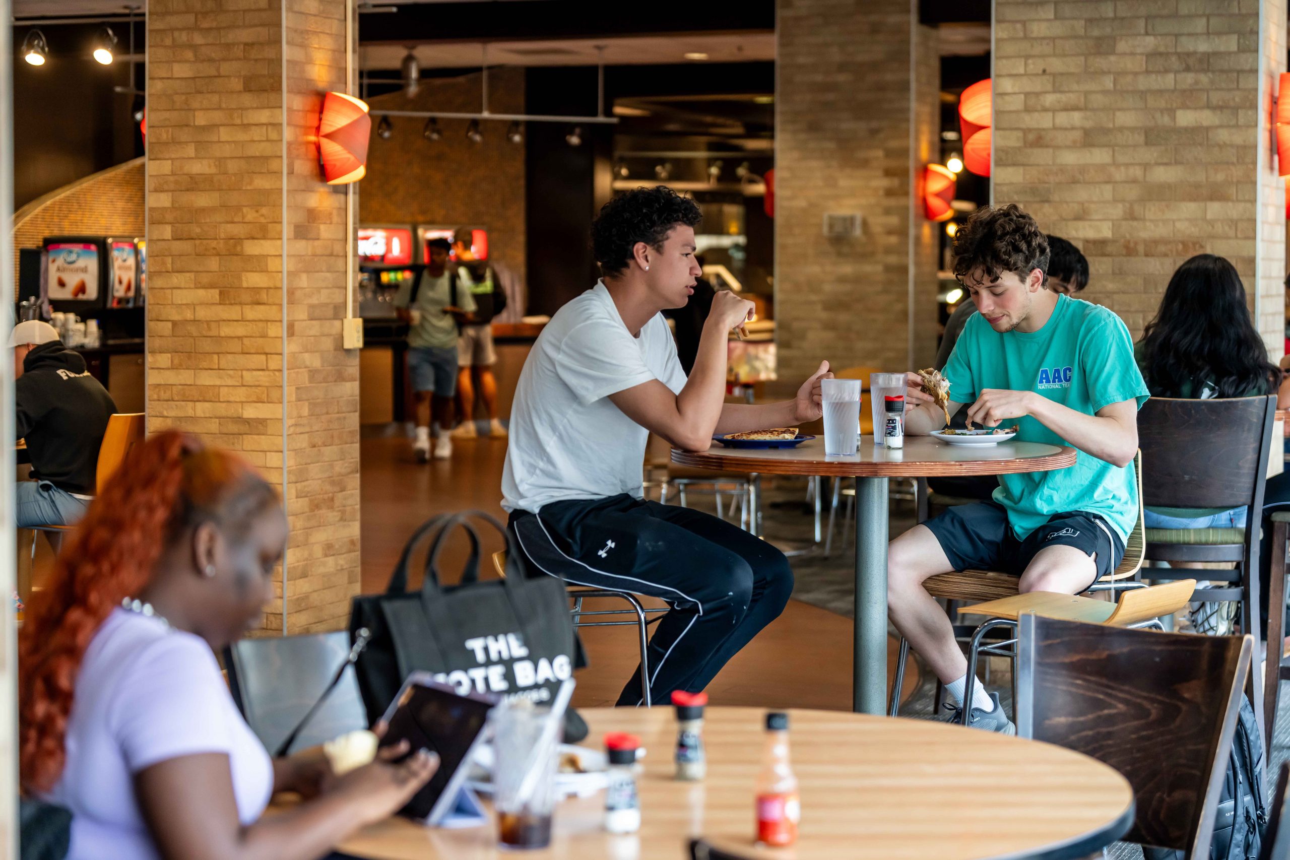 Students sit at a range of high top and normal tables
