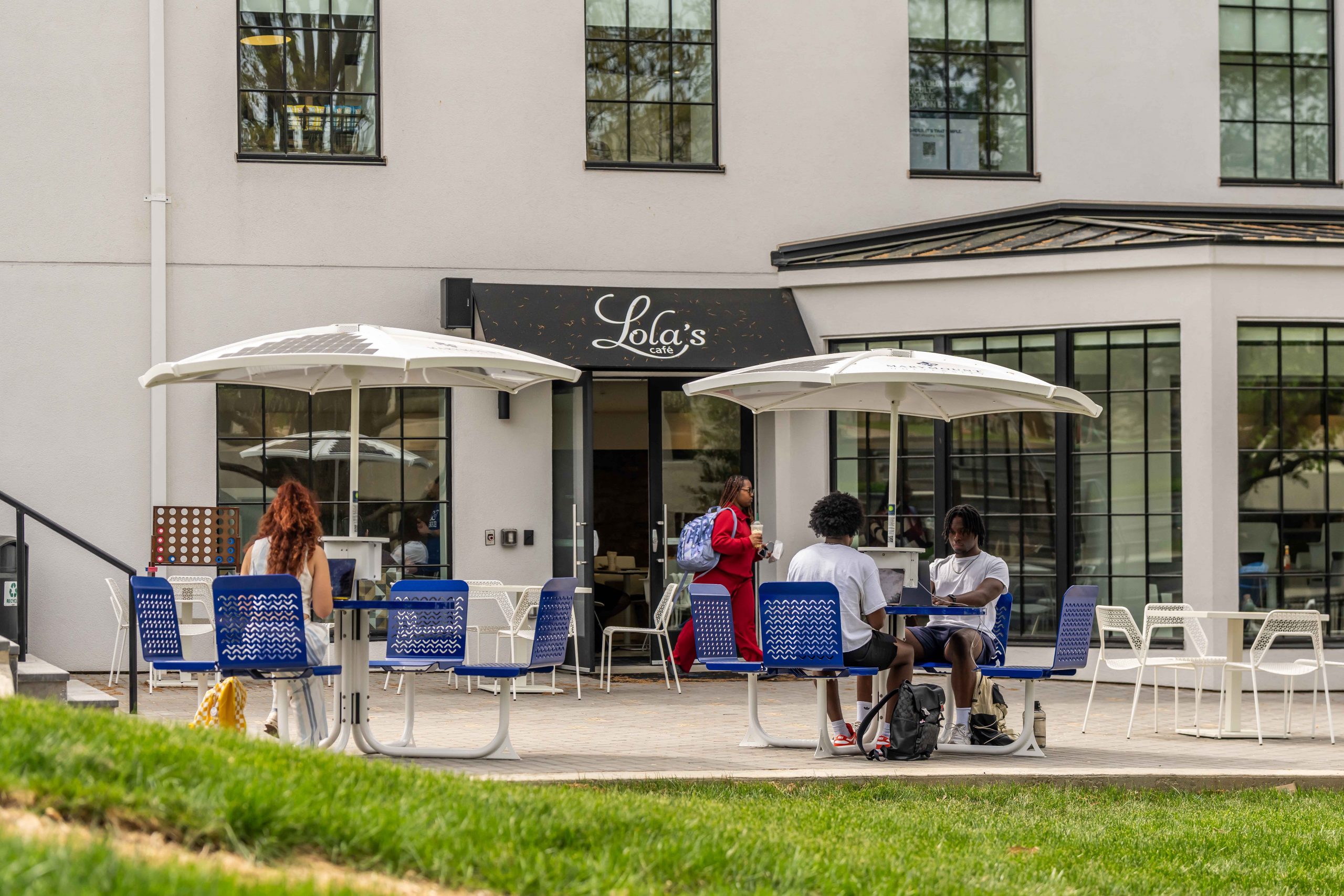 Students sit at picnic tables on a patio