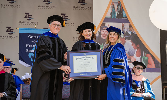 Constance Tolevich Fernandez (center) receives an honorary degree during the College of Health and Education ceremony