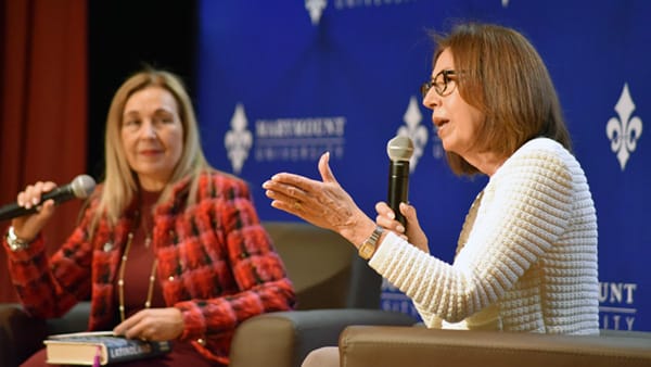 President Irma Becerra and Marie Arana, Literary Director of the Library of Congress and author, sit on stage holding microphones during a lecture.