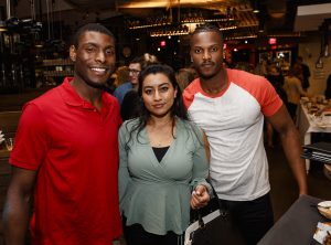 A group of young alumni pose for a photo at a restaurant alumni meetup.