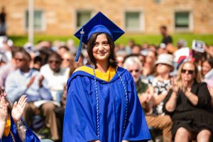 A female graduate stands and is recognized for her achievements during Commencement.