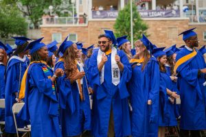 Marymount students in graduation caps and gowns stand together and smile, celebrating commencement weekend.