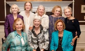 A group of older alumnae pose in two rows. The first row has three