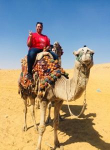 Martinelle Allen poses for a photo while riding on a camel in the desert.