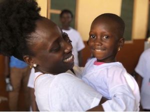 Nana Konadu Asare smiles while holding a young boy,