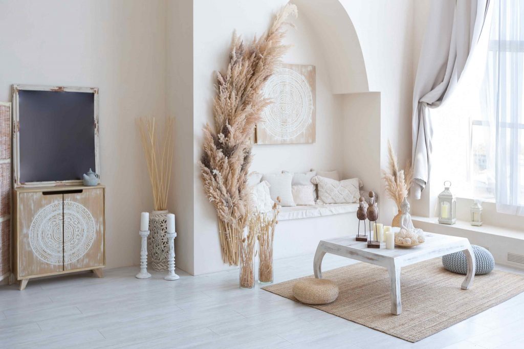 An interior design layout of a living room with a table, chest, pillows and fake plants.