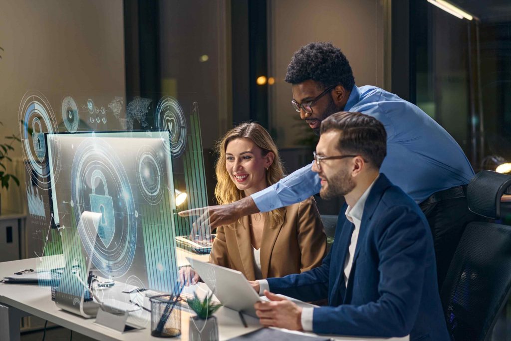 Three people work on and point to a 3D futuristic computer screen.