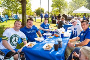 Alumni smile while sitting together during the Homecoming BBQ