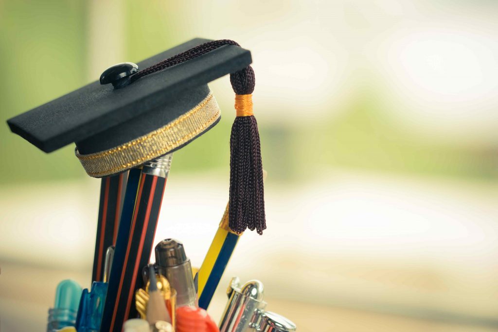 A graduation cap balances on a a cup filled with pencils