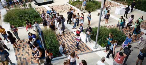 People fill a courtyard, walking around and chatting with each other