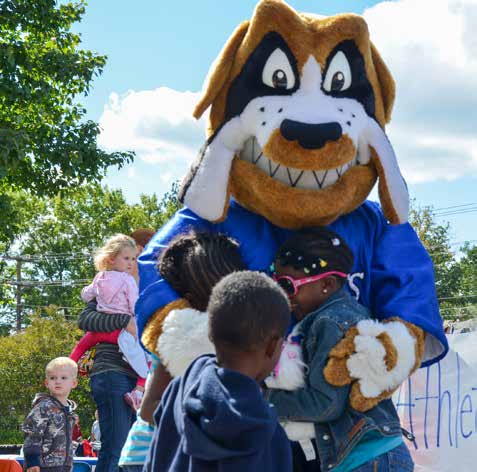 A large mascot St. Bernard hugs children.