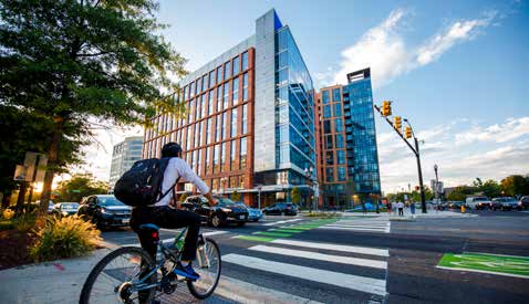 A person on a bicycle approaches a crosswalk in front of the Ballston Center building and intersection