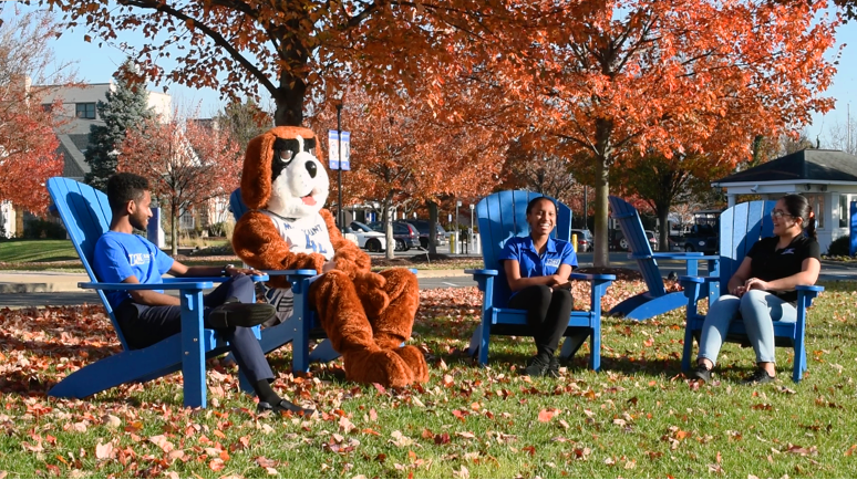 Students sit in Adirondack chairs with Bernie the St. Bernard mascot.
