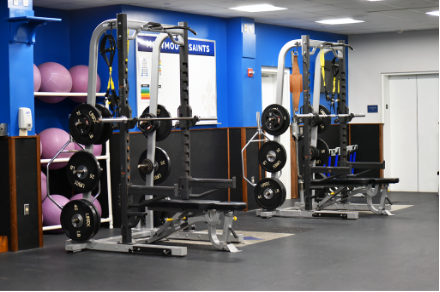 A weight room with a bench and barbell machine.